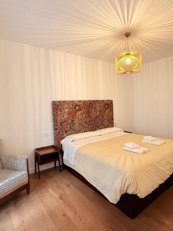 a bedroom with a bed and a chandelier and a chair at Apartamentos Molinos in Constantina