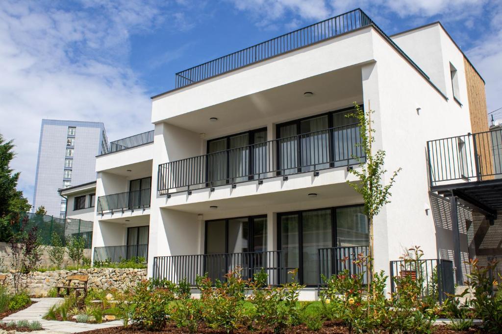 a white building with balconies and plants at Gardinn Apartments - Hotel Service and Free Parking in Bratislava
