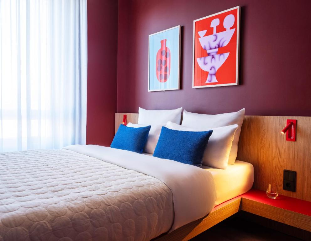 una camera da letto con un grande letto bianco con cuscini blu di Numa Berlin Friedrichshain a Berlino