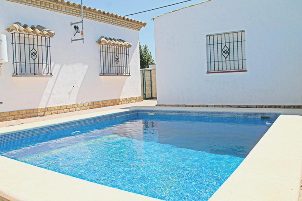 una piscina frente a un edificio blanco en Chalet Arroyo Majadales 108, en Conil de la Frontera