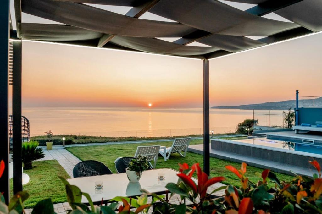 Un patio con vista al mar al atardecer. en Blue Green Villa Kalyves eco pool premium quality, en Kalyves