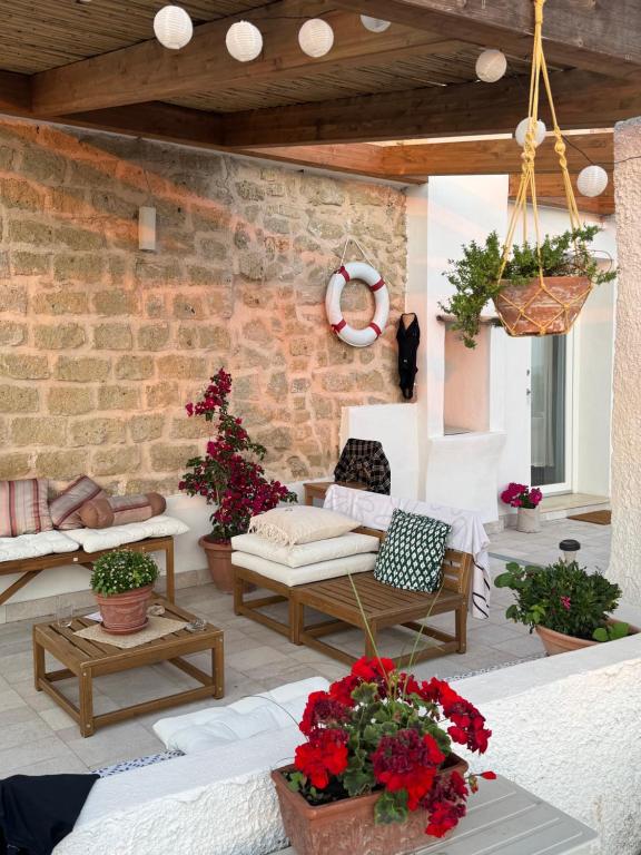 a patio with couches and flowers and a brick wall at Il Panorama di Ercole in Monte di Procida