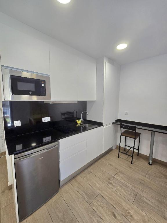 a kitchen with white cabinets and a black counter top at SM Apartments in Lleida