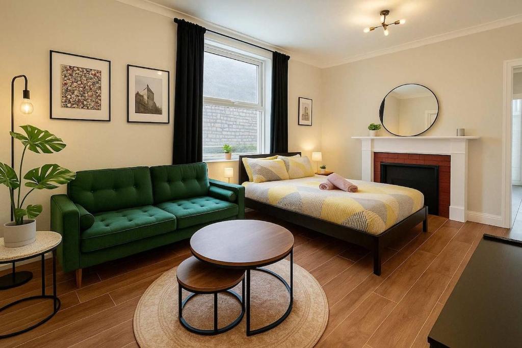 a living room with a bed and a green couch at Central Studio Apartment for 2 in Cardiff