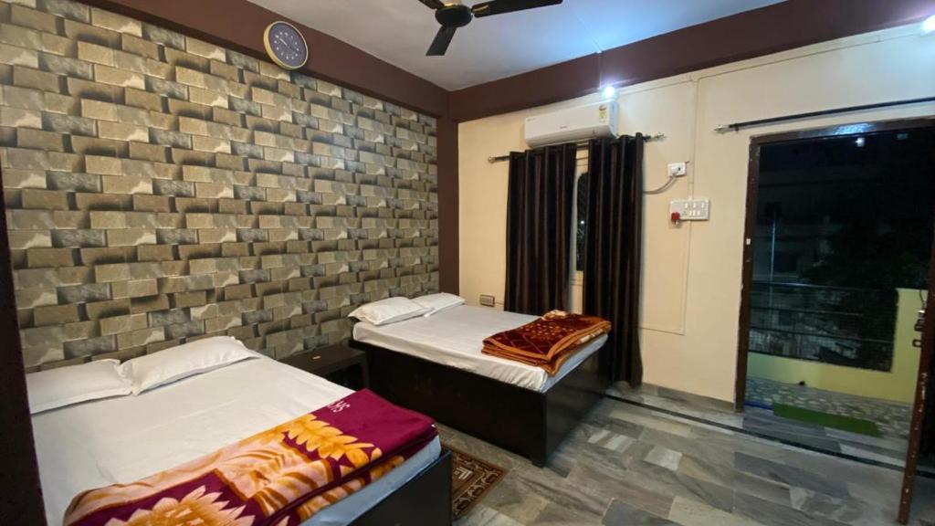 two beds in a room with a brick wall at kashidham home stays in Varanasi