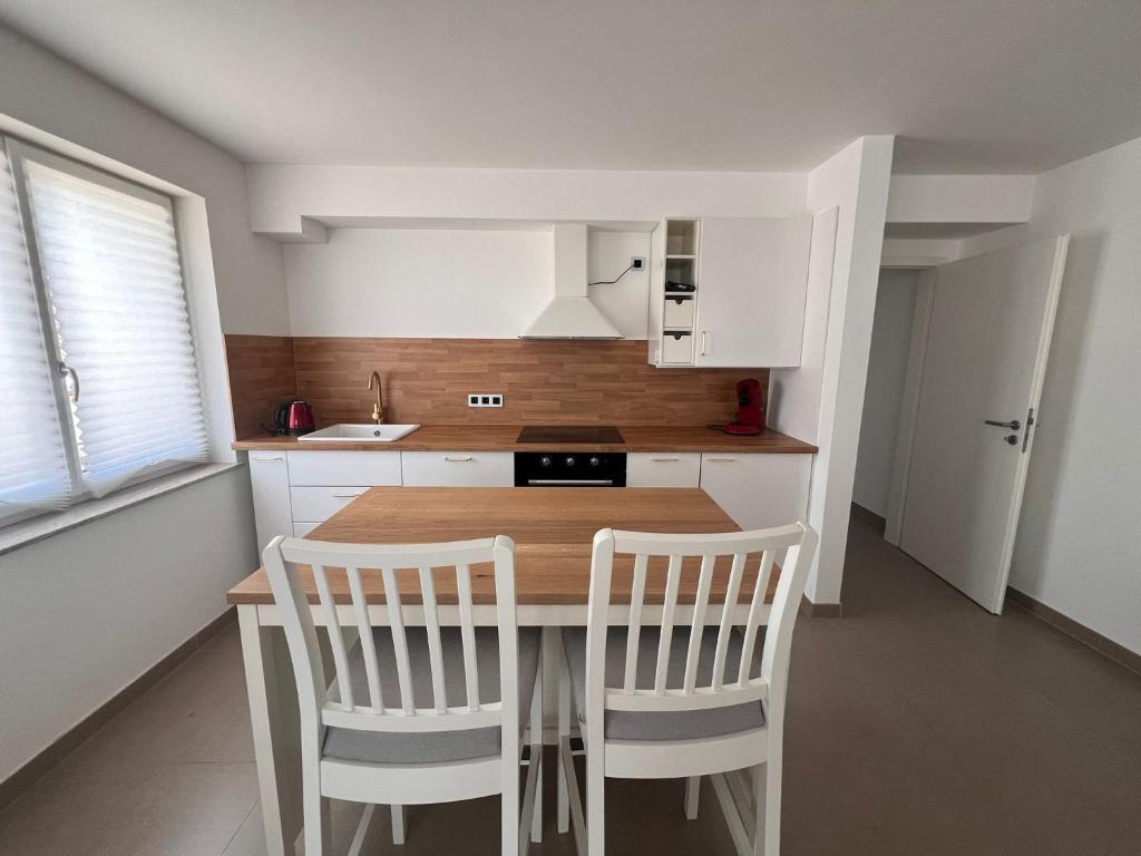 a kitchen with a wooden table and white chairs at Idyllische Ferienwohnung in Ebersbach-Musbach