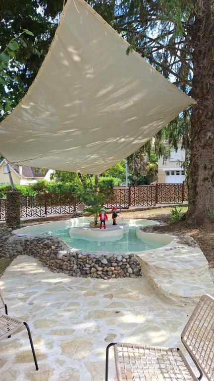 un grand auvent blanc au-dessus d'une fontaine dans un parc dans l'établissement Maison de charme dans Sarlat Attention réservations et arrivées commencent exclusivement le dimanche, à Sarlat-la-Canéda