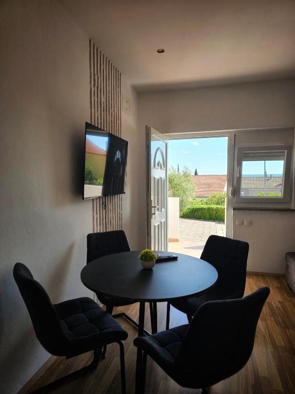 a living room with a table and chairs and a television at Apartment Olive in Maslenica