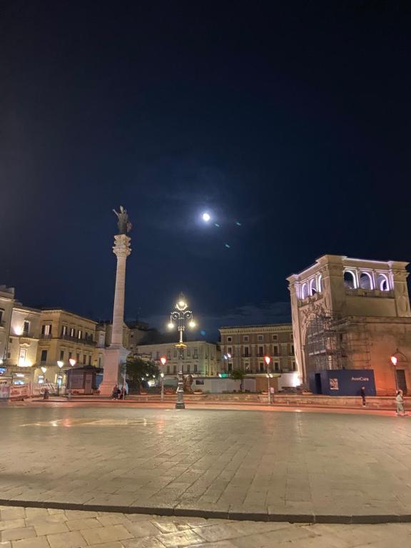 a city square at night with a statue and a moon at LECCE MON AMOUR B&B in Lecce