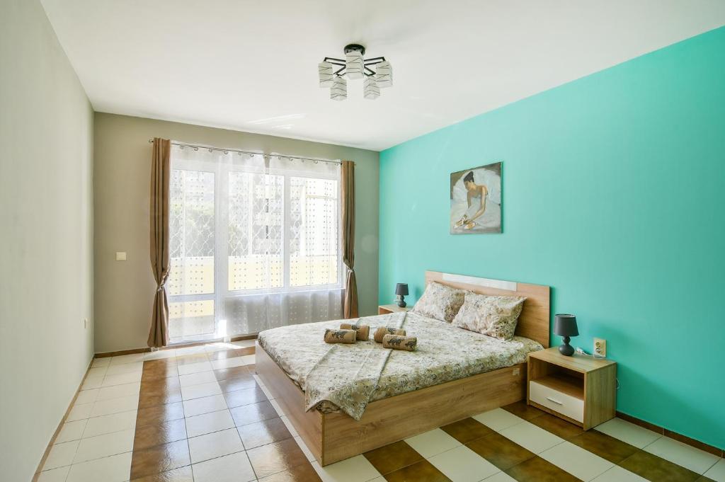 a blue bedroom with a bed and a window at 2BR Spacious Apartment in Varna City