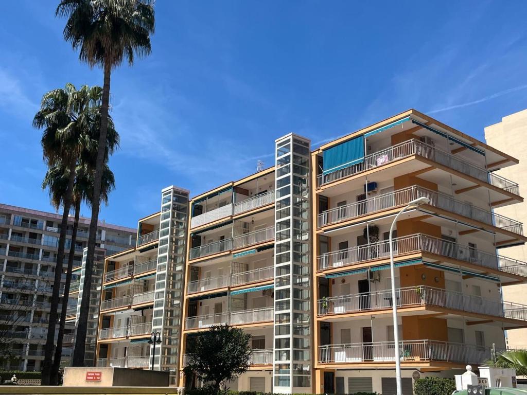 ein Apartmenthaus mit Palmen im Vordergrund in der Unterkunft Wind Rose Gandia Beach in Playa de Gandia