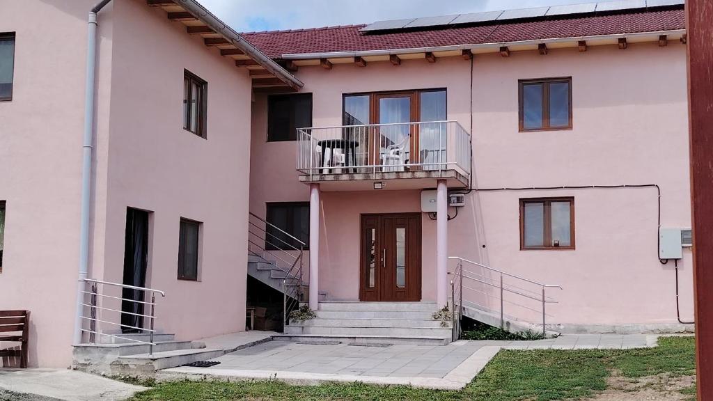 ein rosafarbenes Haus mit einem Balkon und einer Tür in der Unterkunft CASA BIA CRIBO Sannicolau de Munte - bai termale in Săcueni