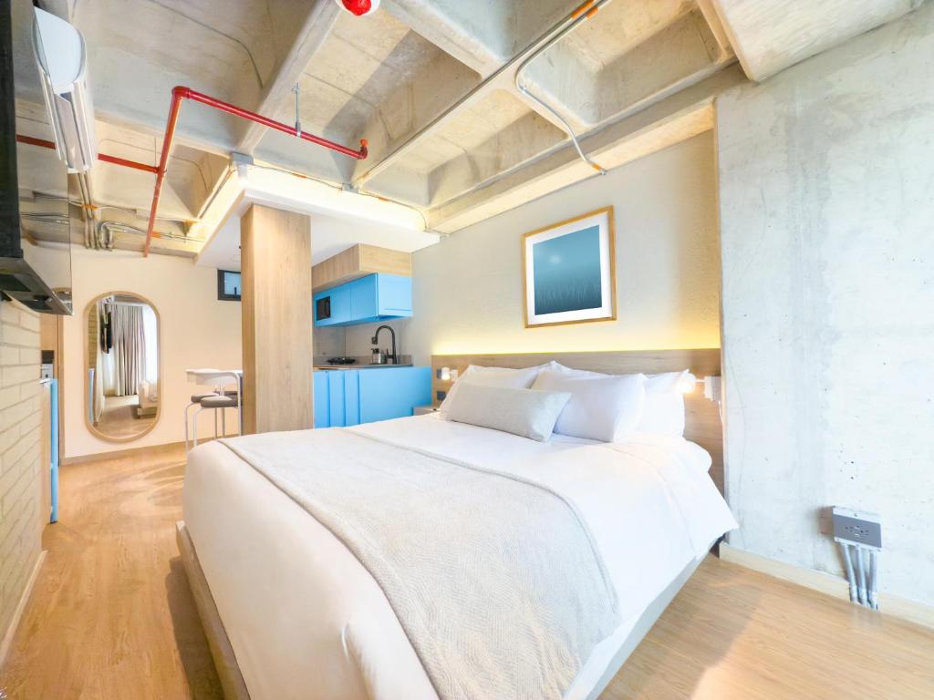 ein Schlafzimmer mit einem großen weißen Bett und eine Küche in der Unterkunft Hotel Once22 in Sabaneta