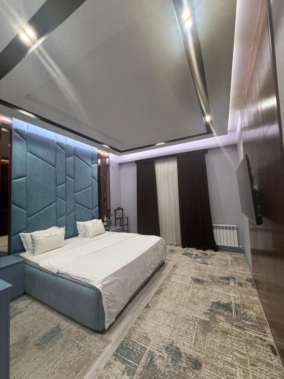 a bedroom with a large bed with a blue headboard at Gardens resident Tashkent city in Tashkent