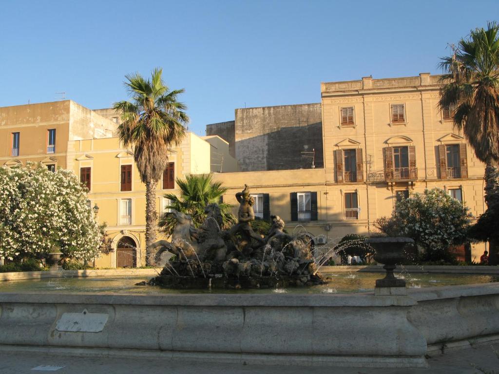 a fountain in front of a building with palm trees at Piazza Vittorio 30 in Trapani