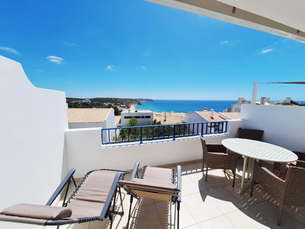 een balkon met een tafel en stoelen en uitzicht op de oceaan bij Casa Calma in Salema