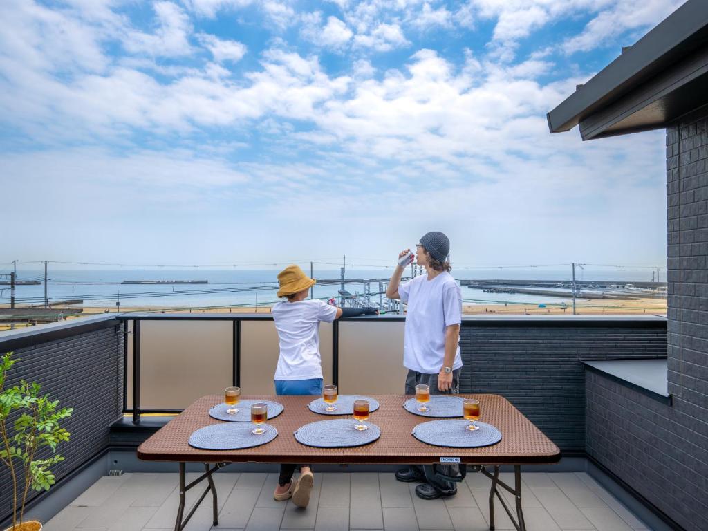een man en een jongen staan op een balkon met een tafel bij Town House Suma in Kobe