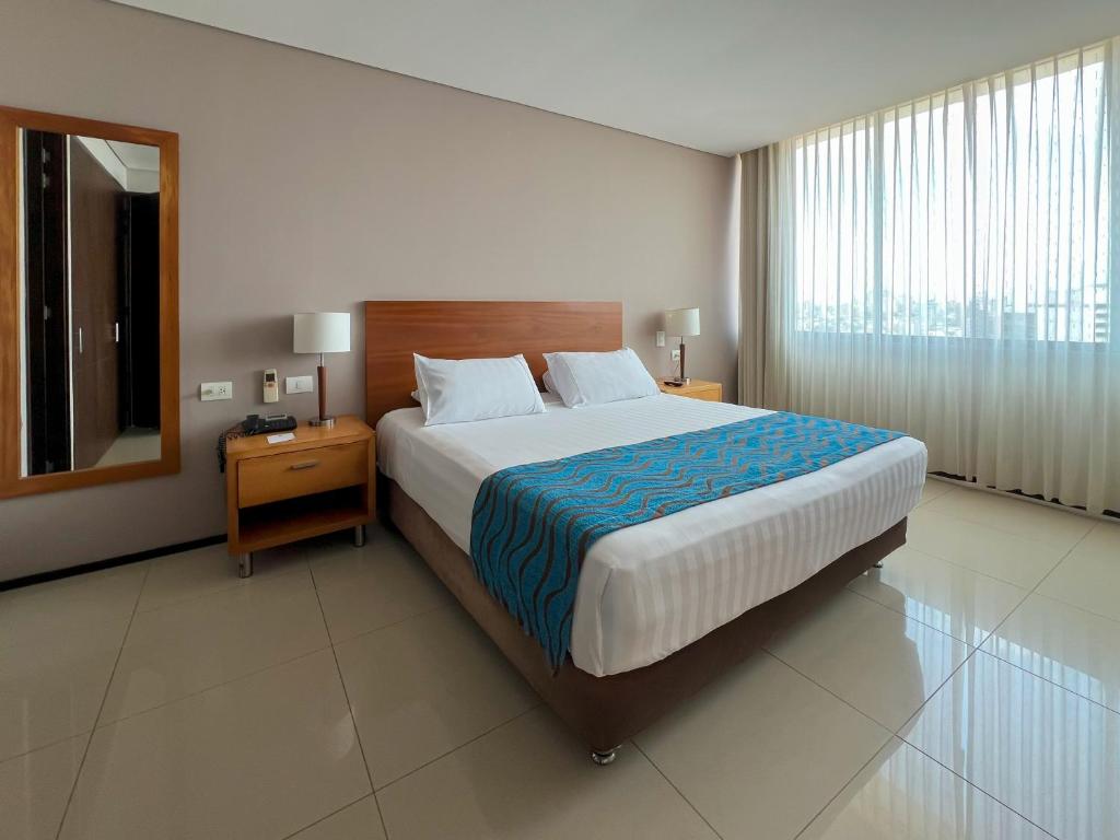 a bedroom with a large bed and a mirror at Estelar Apartamentos Barranquilla in Barranquilla