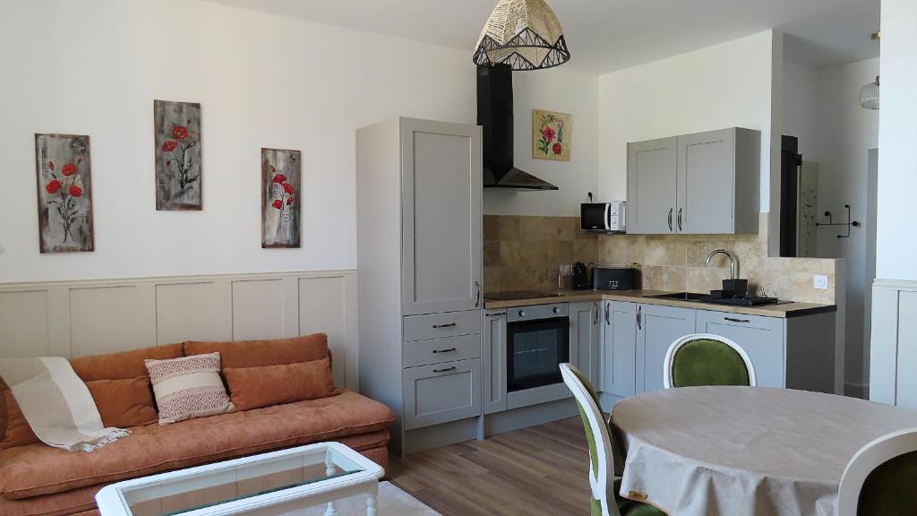 a kitchen and living room with a couch and a table at Les échappées de Senonches in Senonches