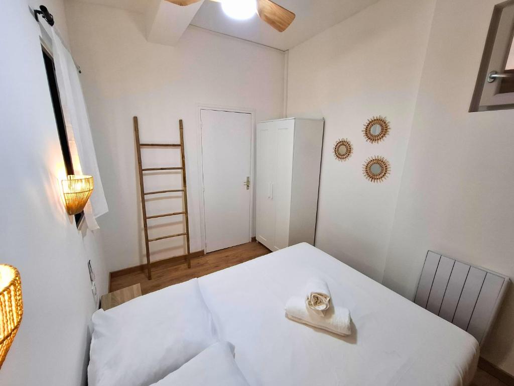a room with a white bed with a towel on it at T2 Cosy Clim & WiFi - Ecusson cœur de Montpellier in Montpellier