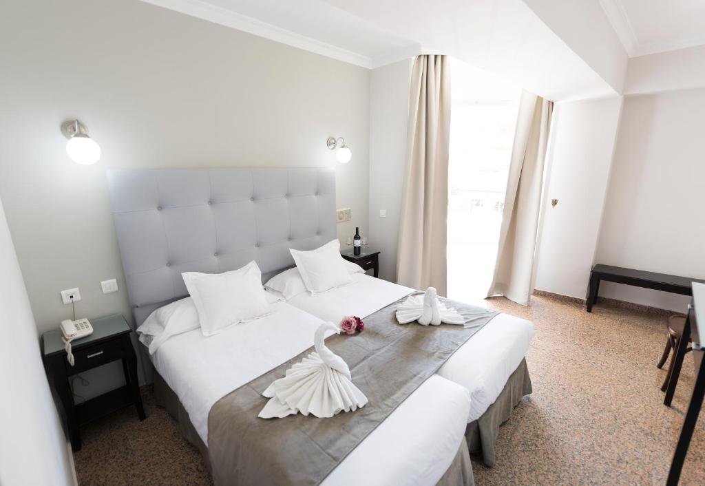 a bedroom with a large white bed with towels on it at Hotel Toboso Chaparil in Nerja