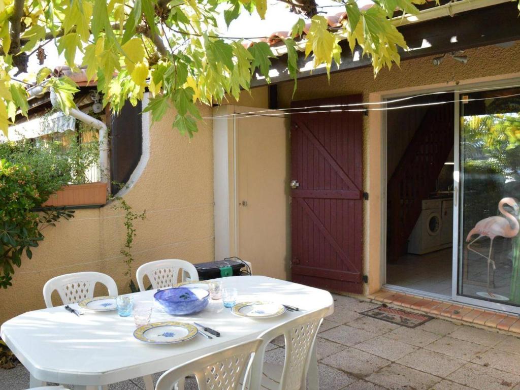 une table blanche avec des chaises blanches et un flamingo rose dans l'établissement Maison bord de mer 8 pers. avec terrasse, parking privé, animaux acceptés, ménage inclus - FR-1-225D-616, à Saint Cyprien Plage