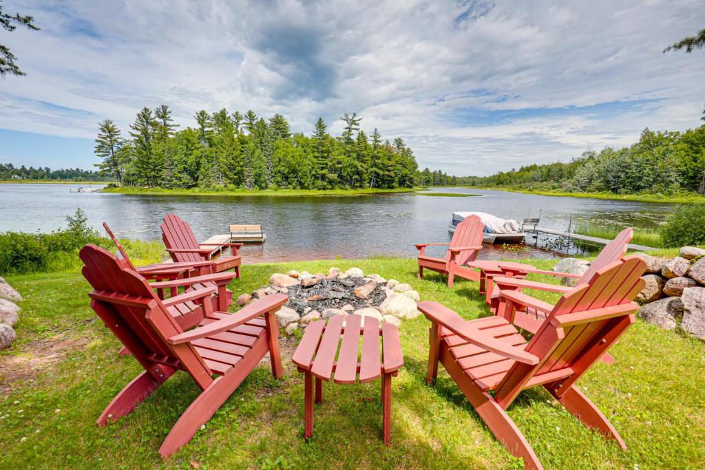 a group of chairs sitting around a fire pit next to a lake at Dock, Fire Pit Historic Lakefront Cabin in Mercer in Mercer