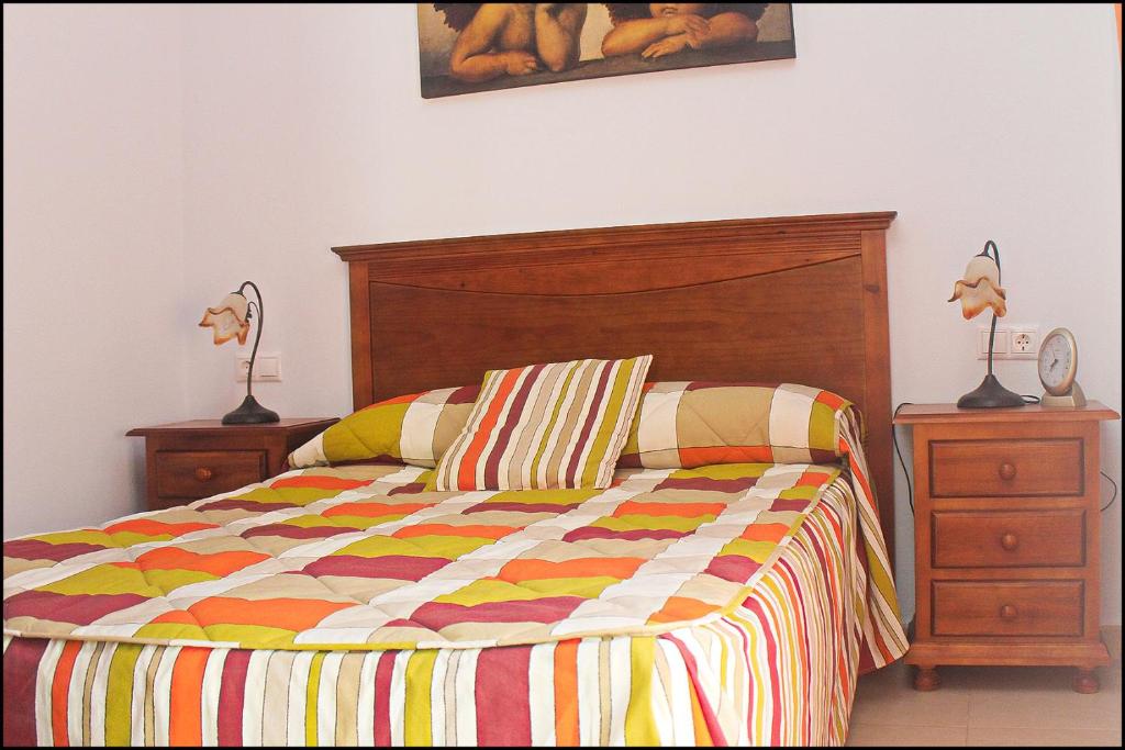 una cama con un edredón colorido y 2 mesitas de noche en Apartamento Pascual Junquera II, en Conil de la Frontera