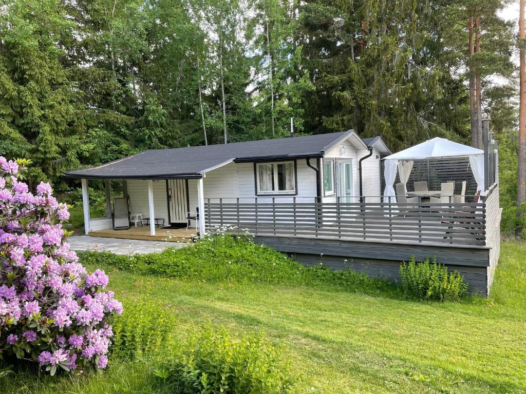 a small white house with a porch and a yard at Gäststuga i mysiga Sparreholm in Sparreholm