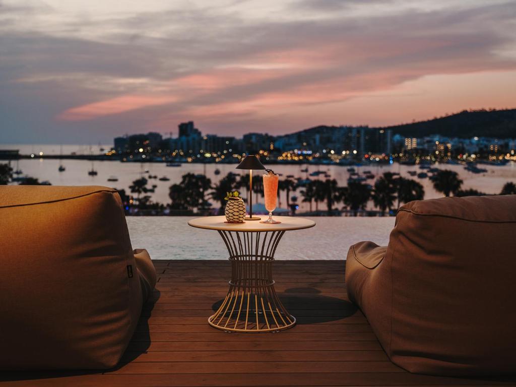 a table with a lamp sitting on a deck with a view of the water at Bonito Ibiza by O Beach - New Opening 2025 in San Antonio