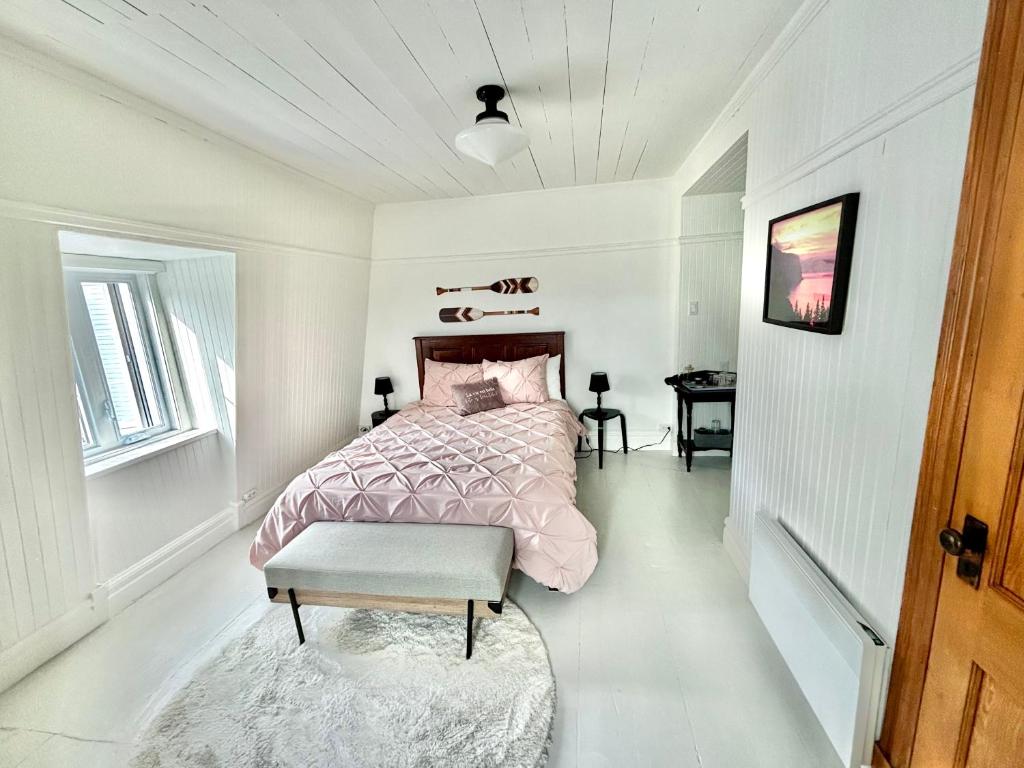 een witte slaapkamer met een bed en een tafel bij Auberge musicale Pour un Instant in La Malbaie