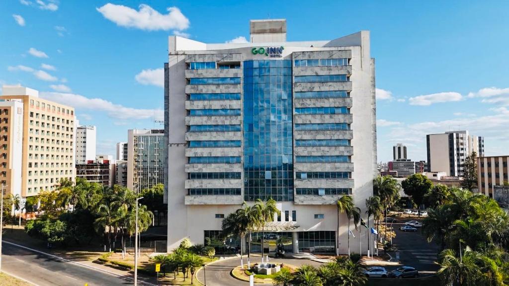 a large office building in a city with palm trees at Quarto Mobiliado no Hotel Go Inn Taguatinga com Wi-Fi, Ar Condicionado e Estacionamento Grátis in Brasília
