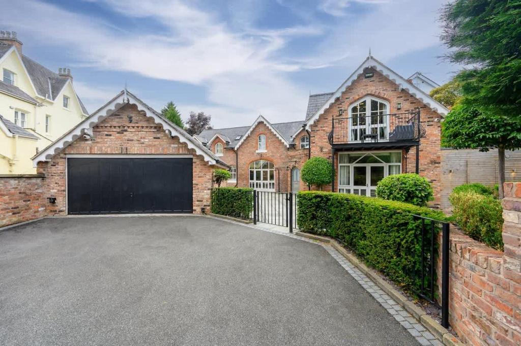 a brick house with a garage in the driveway at Luxurious Bowdon Mansion by City SuperHost in Bowdon