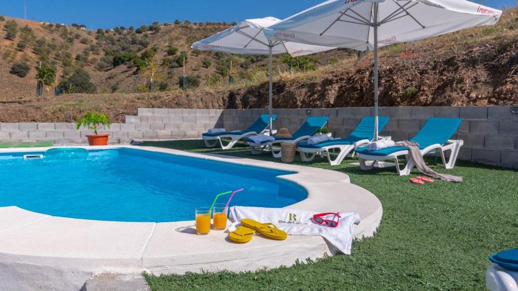 a swimming pool with chairs and an umbrella next to it at Casa Esperanza Sedella by Ruralidays in Sedella