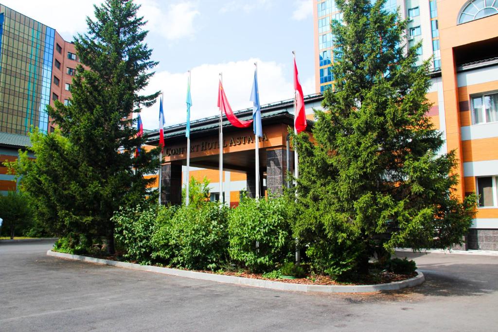a building with flags and trees in front of it at Comfort Hotel Astana in Astana