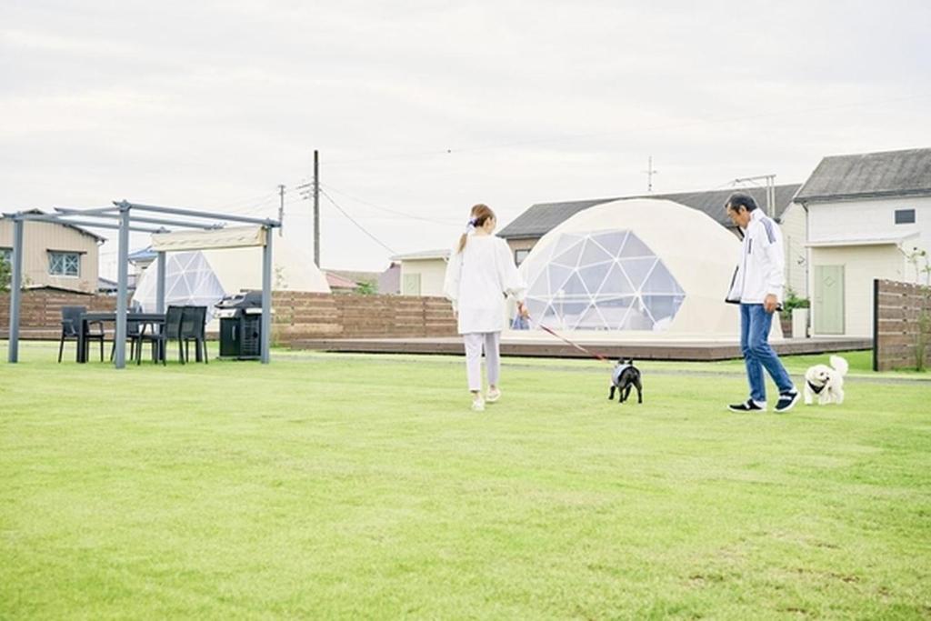 KatakaiにあるEIGHT VILLAGE - Vacation STAY 40441vの白衣を着た二人が野原で二匹の犬を散歩させている