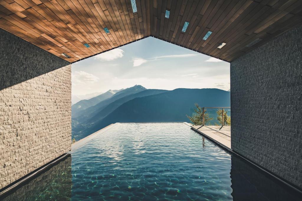 a infinity pool with a view of the mountains at Miramonti Boutique Hotel in Avelengo