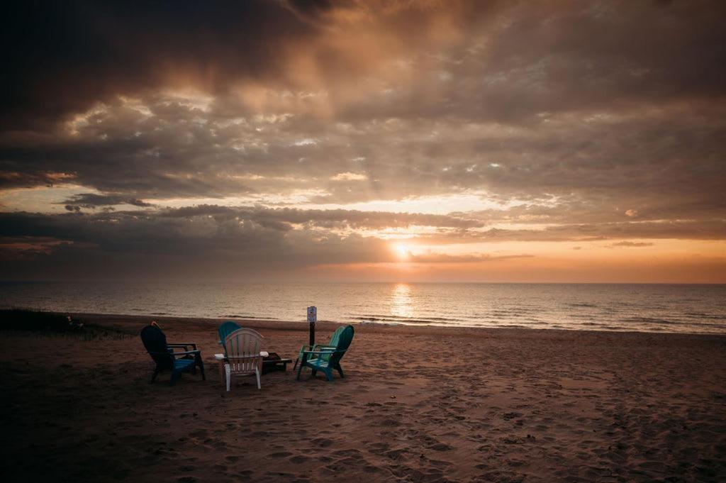 four chairs and a table on the beach at sunset at New renovated bathroom & new roof - Lake Huron 4 in Lincoln Junction