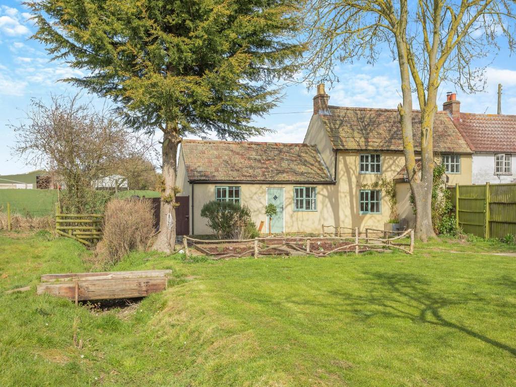 Rookery Cottage في Little Staughton: منزل به سياج وشجرة في الفناء