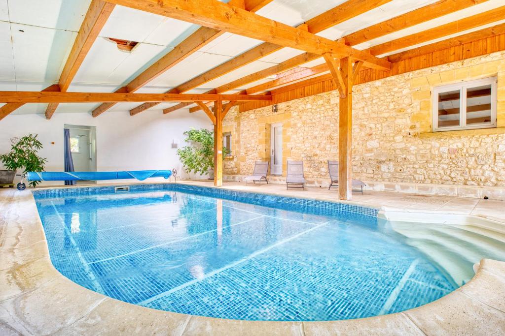 - une grande piscine dans une maison dotée d'un mur en pierre dans l'établissement La Roulotte Rouge, à Monsac
