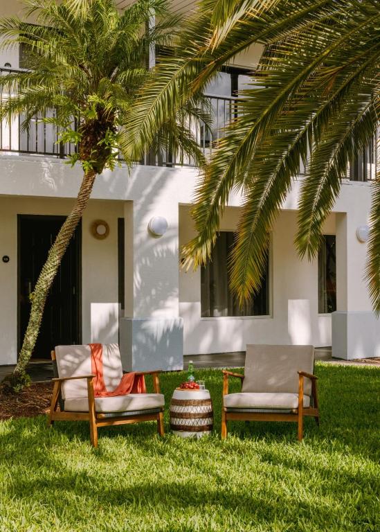 two chairs and a palm tree in front of a house at voco Kissimmee Orlando by IHG in Orlando
