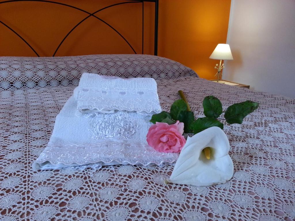 ein Bett mit einem Handtuch, einer Rose und einem Strauß in der Unterkunft Il Piccolo Baglio in Valderice