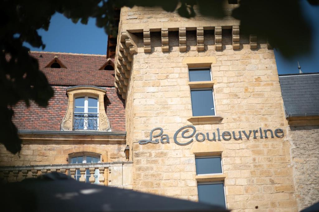 un bâtiment avec une enseigne sur le côté dans l'établissement Hôtel La Couleuvrine Sarlat Centre Ville, à Sarlat-la-Canéda