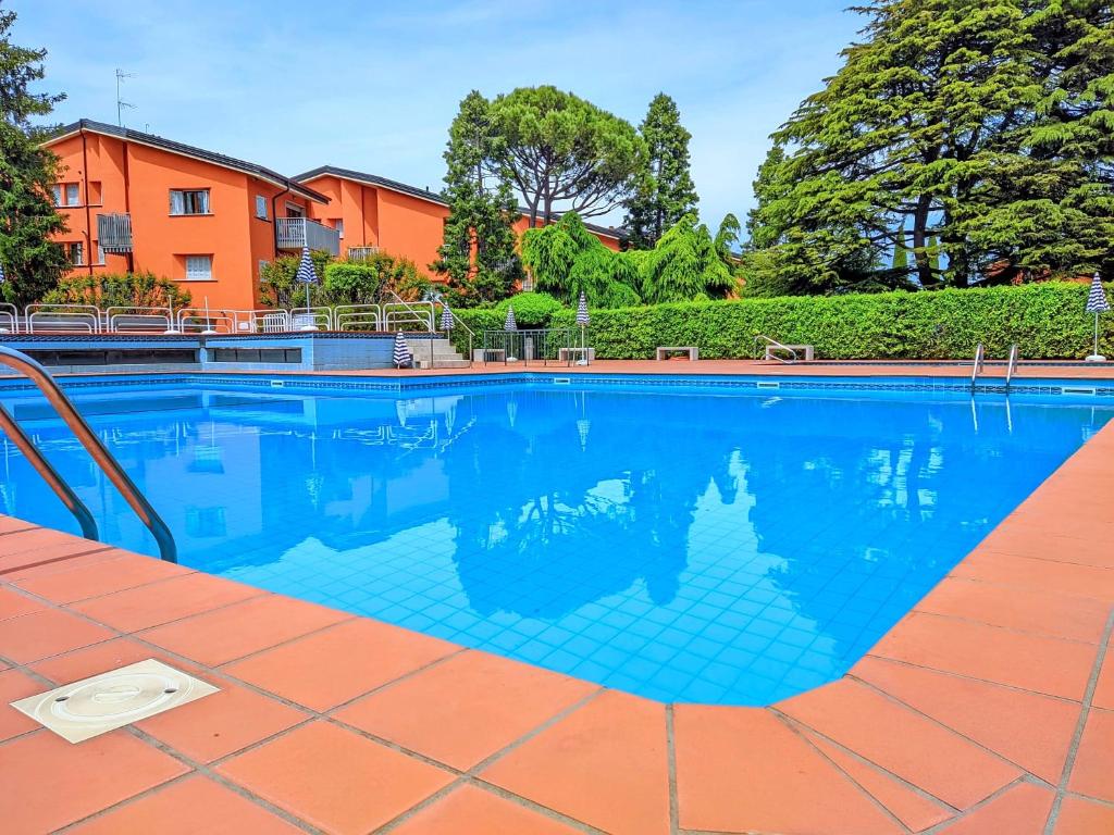 Una piscina con agua azul frente a un edificio. en Cappuccini Friends, en Peschiera del Garda