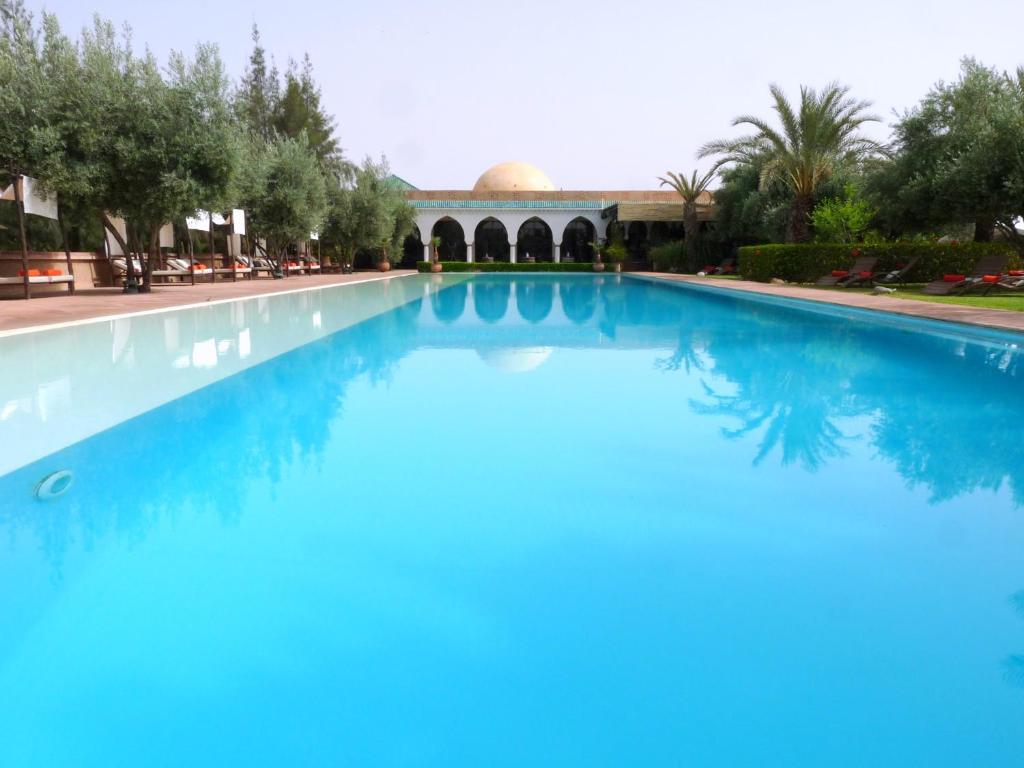 a large blue swimming pool with a building in the background at Manzil La Tortue in Douar Caïd Layadi