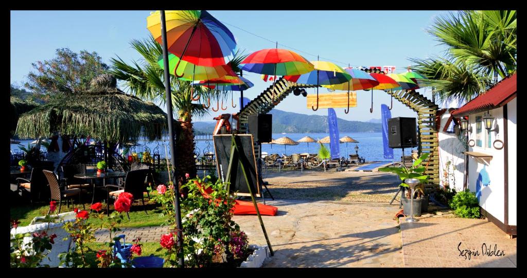 eine Terrasse mit Sonnenschirmen, Tischen und Stühlen am Strand in der Unterkunft Blu Brezza Marine Hotel in Hisarönü