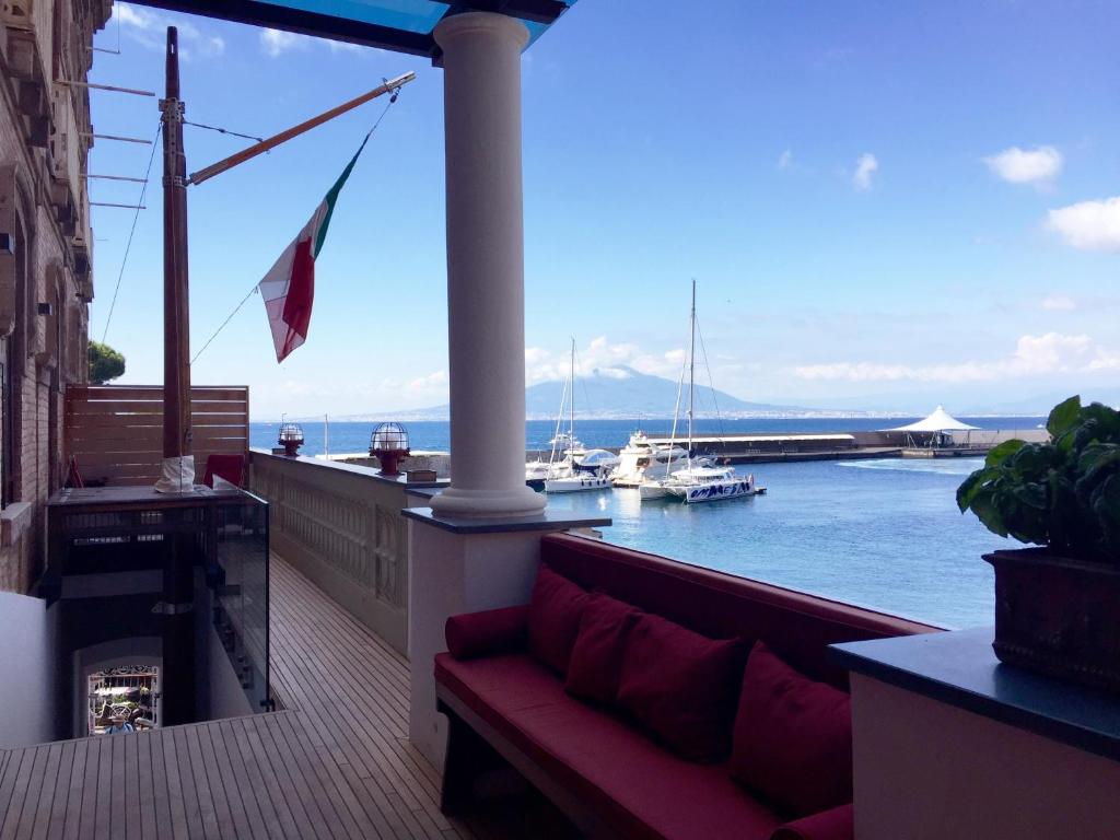 balcone con divano e vista sull'acqua di Yacht Club Capo Cervo Suites B&B a Sorrento