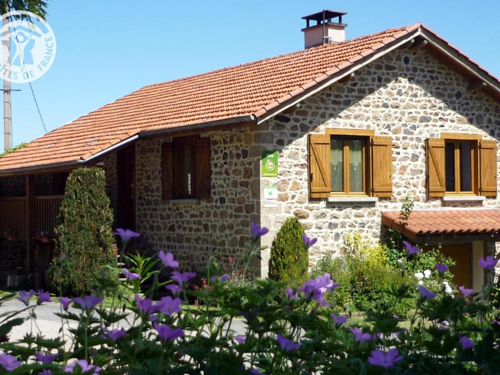 kamienny dom z brązowymi oknami i fioletowymi kwiatami w obiekcie Gîte chaleureux à Sauvain avec jardins, activités familiales et spa en option - FR-1-496-94 w mieście Sauvain