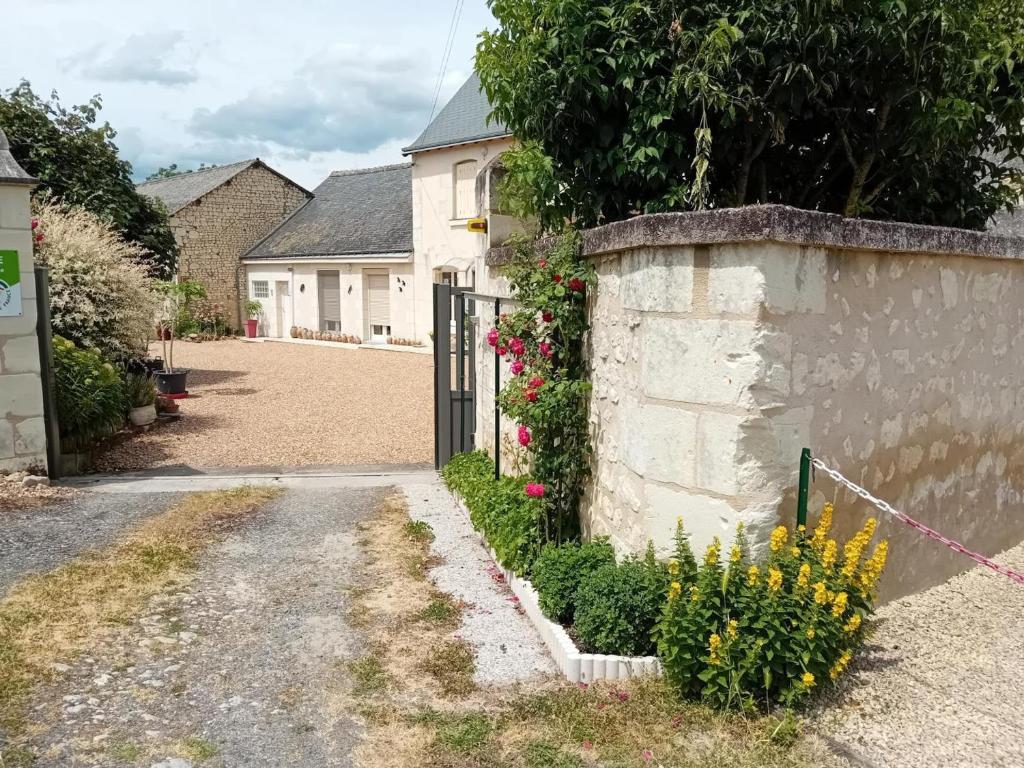 una casa con una puerta y flores en un patio en Charmant gîte en pierre près de Chinon, jardin privatif - FR-1-381-608, en Sazilly