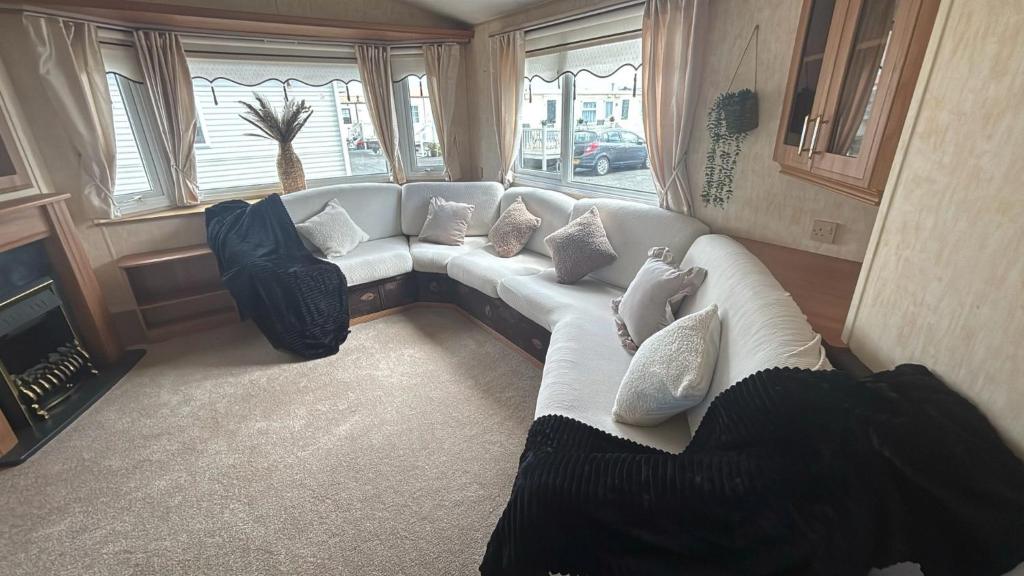a living room with a white couch and windows at 8 Berth Caravan on Edwards Park, Towyn in Kinmel Bay
